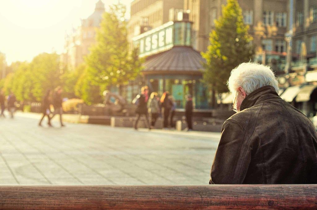 Older man sat on bench in town